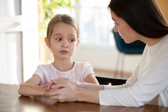 Archivo - Head shot unhappy small child girl sitting at table with worrying mother, sharing school problems. Compassionate caring attentive mommy having trustful conversation with unhappy offended daughter.